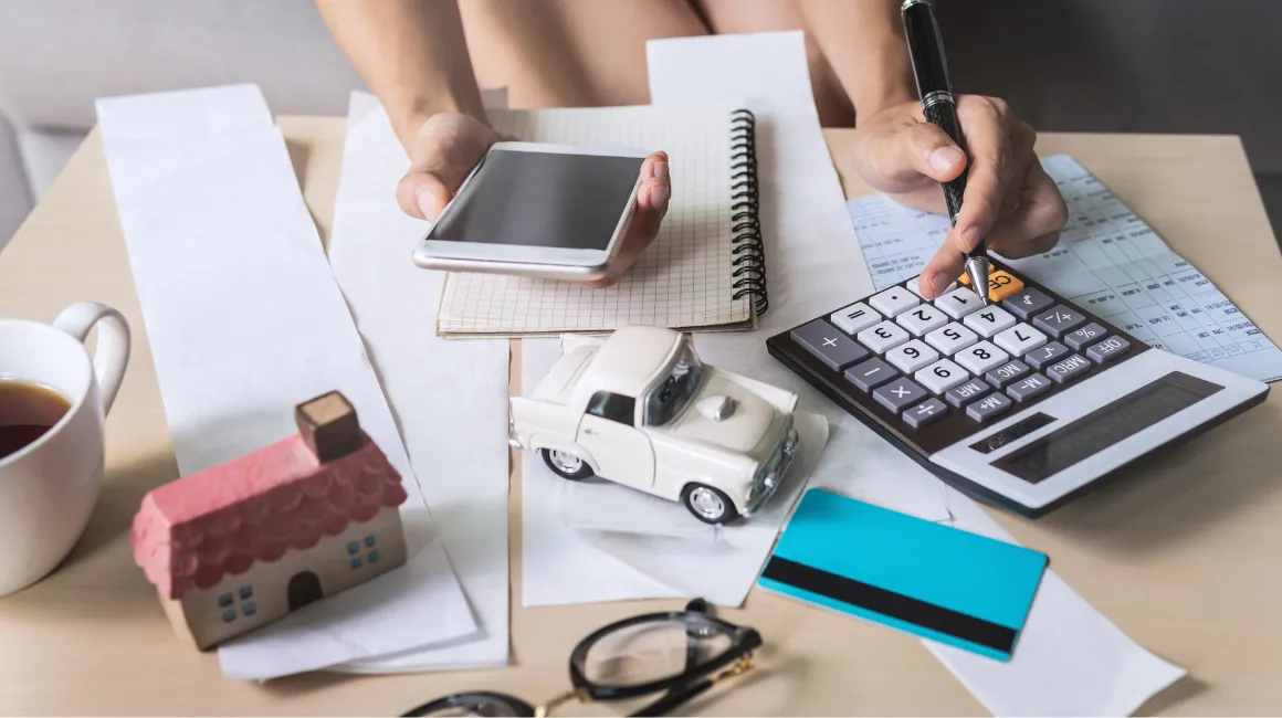 Obliczanie rat kredytów i wydatków domowych – kobieta z kalkulatorem, telefonem i dokumentami finansowymi 