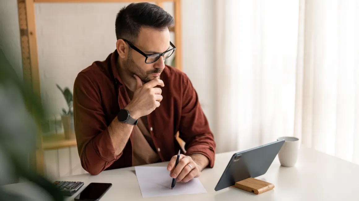 Mężczyzna analizujący dane przed tabletem przy biurku
